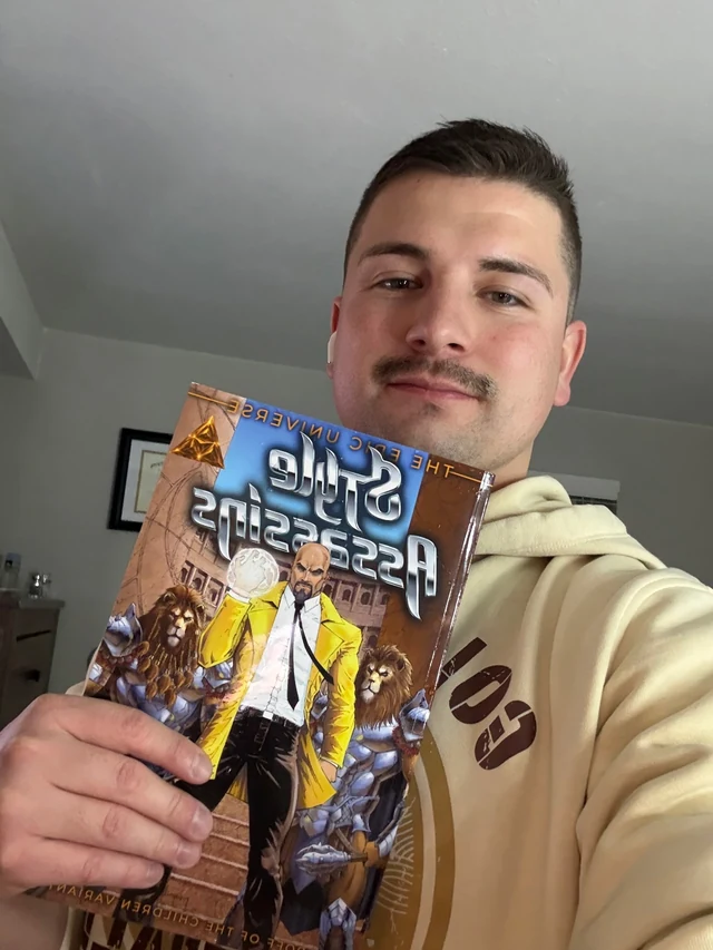 Reader holding a Style Assassins comic with The Children and Darcs cover in a mirrored selfie.