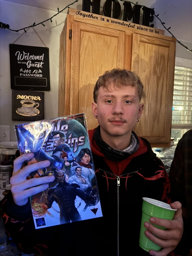 Reader holding the Style Assassins standard-cover comic and a green cup.